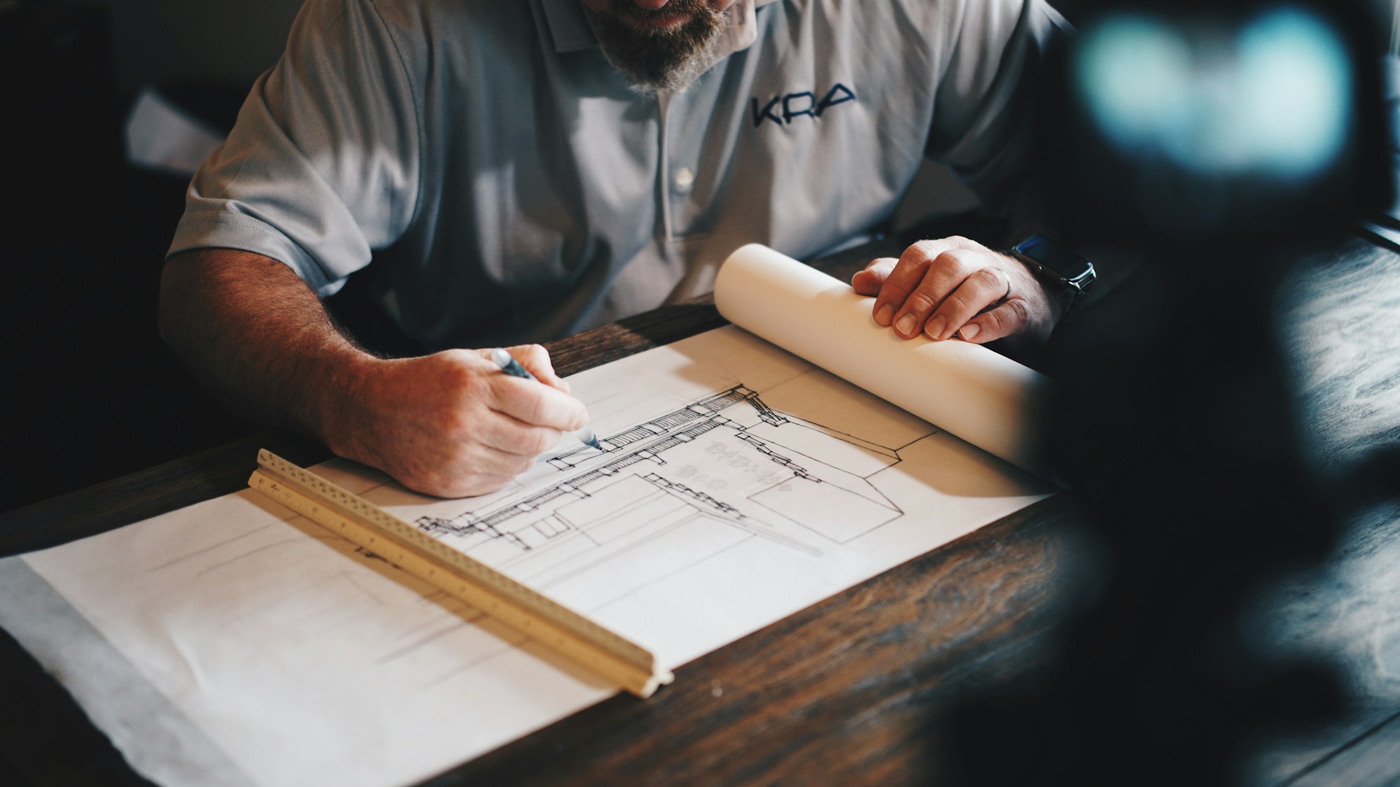An architect drafting a building plan with pencil and ruler